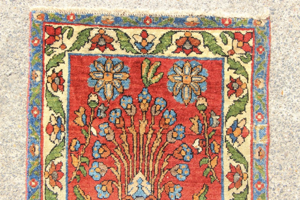 An antique hand-knotted Persian Sarouk rug runner featuring a vibrant crimson field decorated with floral motifs within a patterned border. View IV