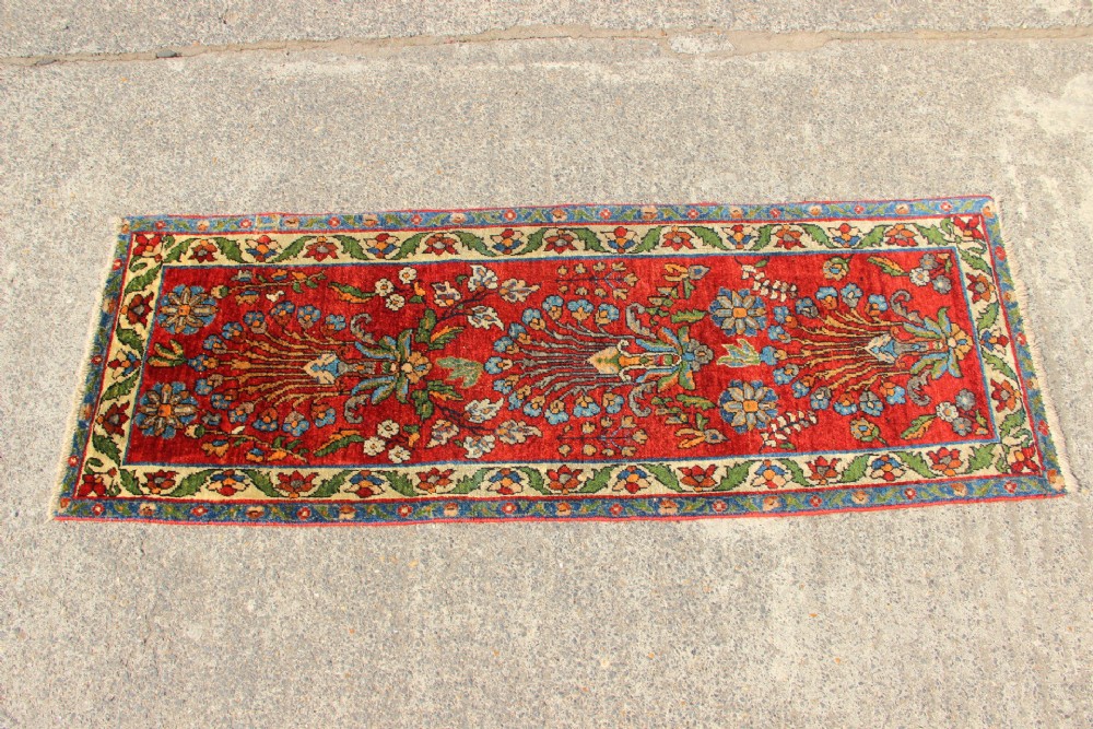 An antique hand-knotted Persian Sarouk rug runner featuring a vibrant crimson field decorated with floral motifs within a patterned border. View VI