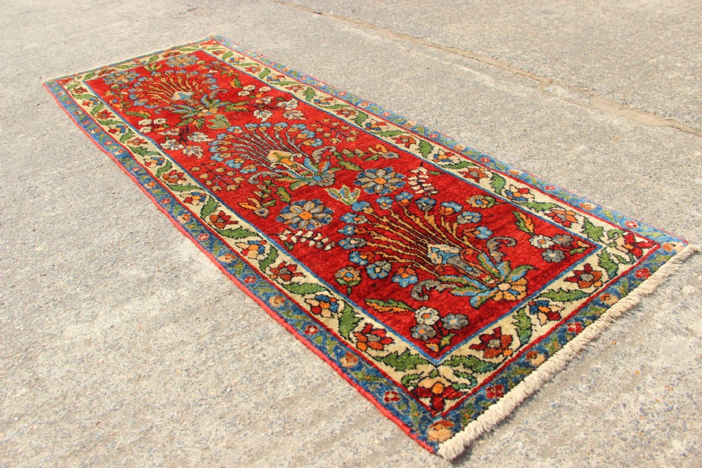 An antique hand-knotted Persian Sarouk rug runner featuring a vibrant crimson field decorated with floral motifs within a patterned border. View VII