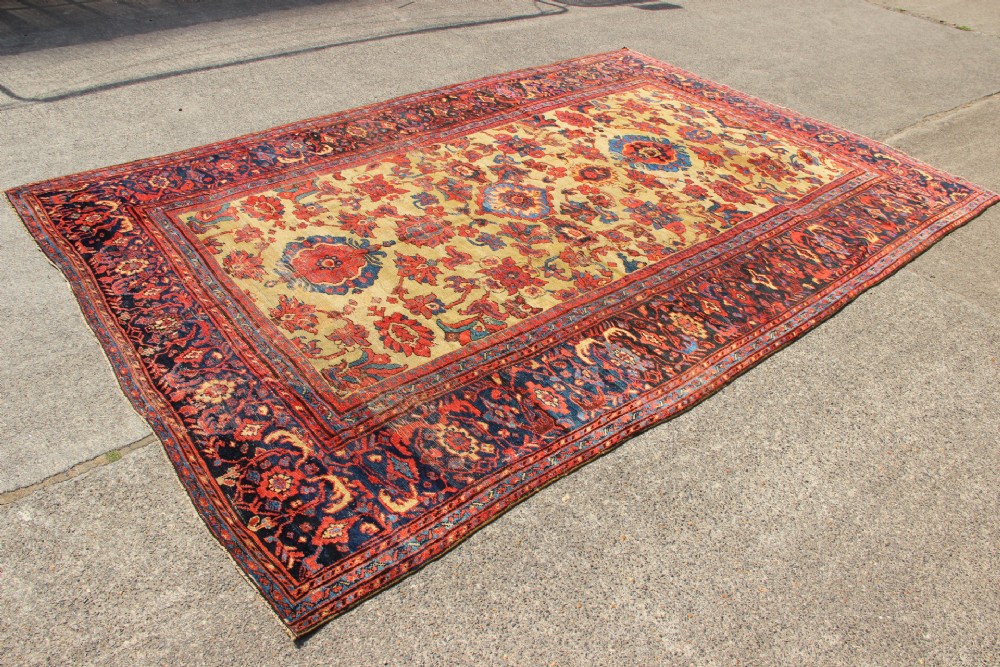 An antique hand-knotted Fereghan Persian carpet featuring a central cream field filled with red and navy floral motifs framed by a wide geometric border. View II