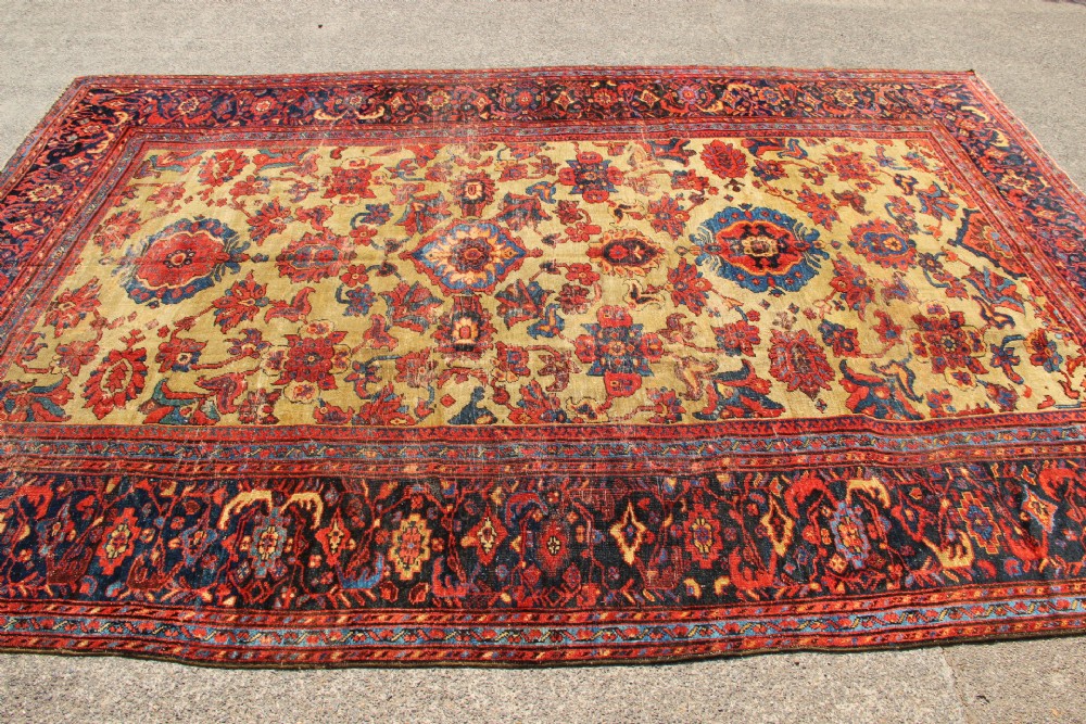 An antique hand-knotted Fereghan Persian carpet featuring a central cream field filled with red and navy floral motifs framed by a wide geometric border. View III