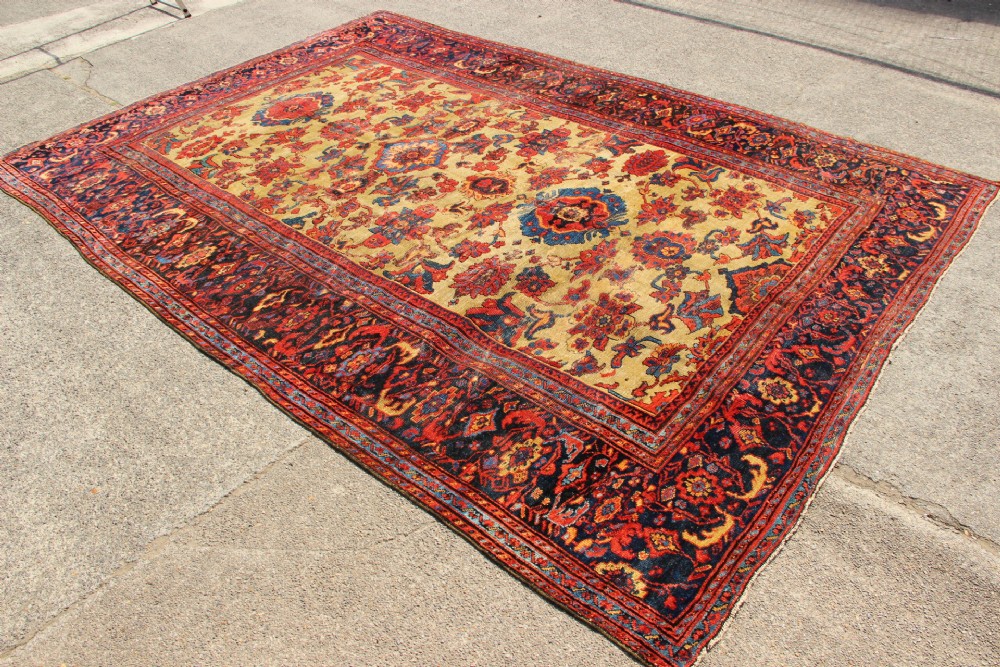 An antique hand-knotted Fereghan Persian carpet featuring a central cream field filled with red and navy floral motifs framed by a wide geometric border. View IV
