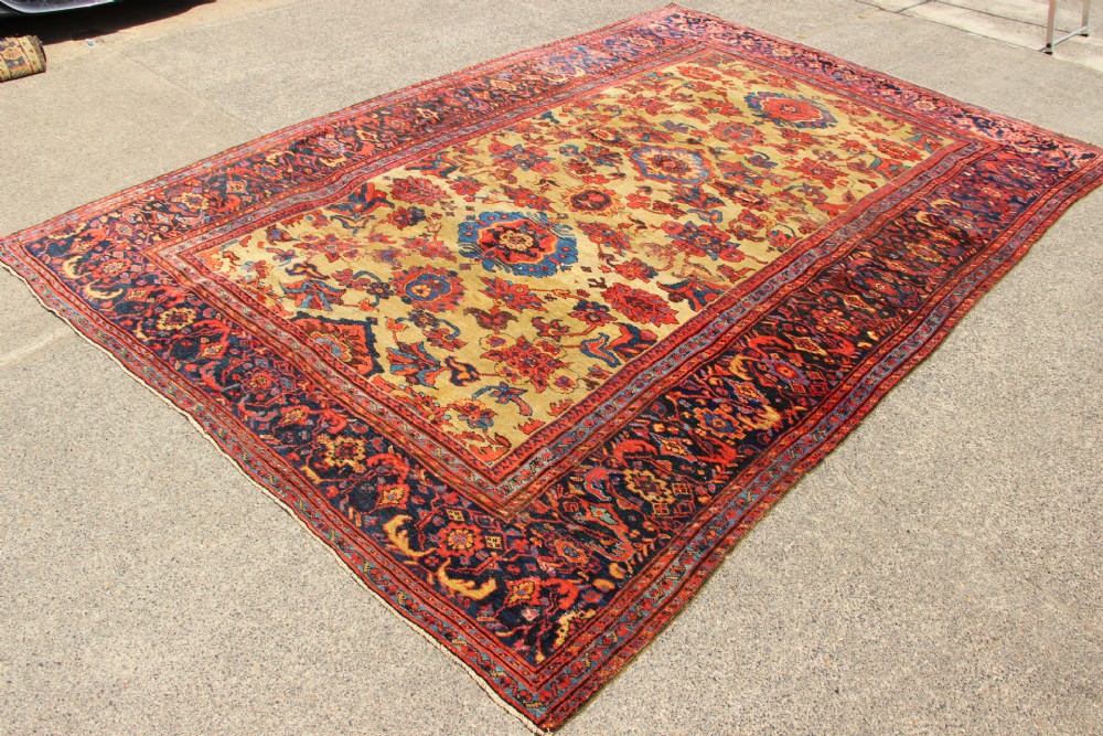 An antique hand-knotted Fereghan Persian carpet featuring a central cream field filled with red and navy floral motifs framed by a wide geometric border. View V