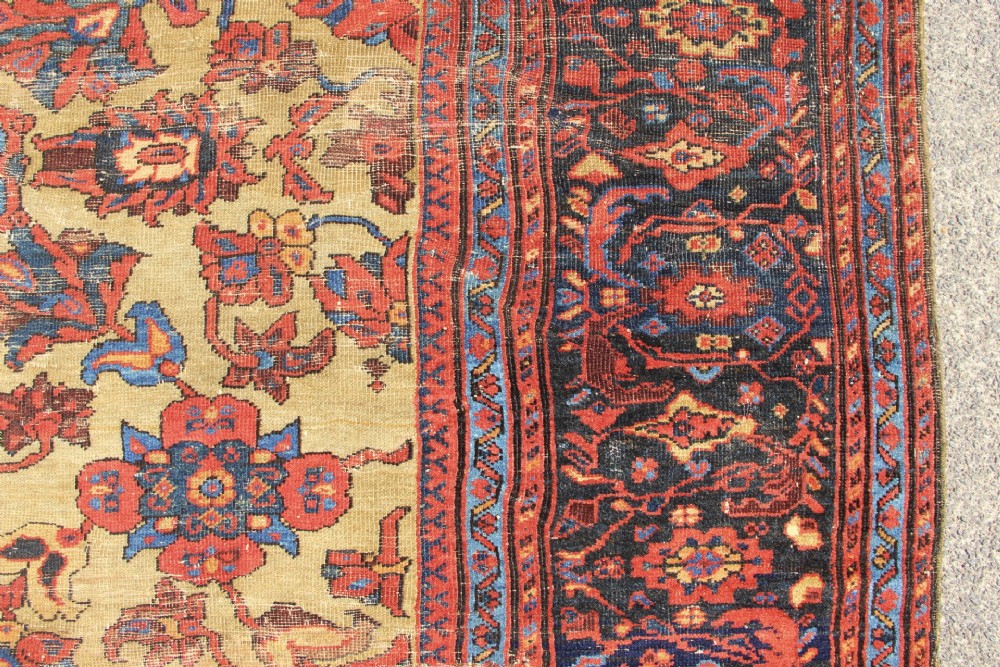 An antique hand-knotted Fereghan Persian carpet featuring a central cream field filled with red and navy floral motifs framed by a wide geometric border. View VII