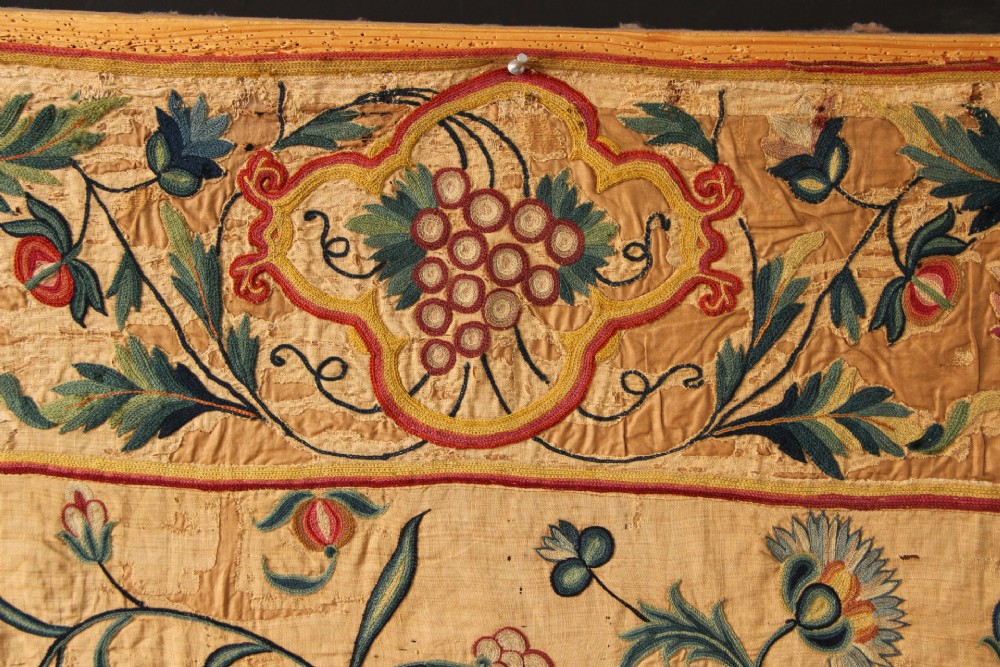 A large rectangular antique English crewelwork panel with intricate hand-embroidered floral tendrils in green, blue, and red wool on a cream background. View II