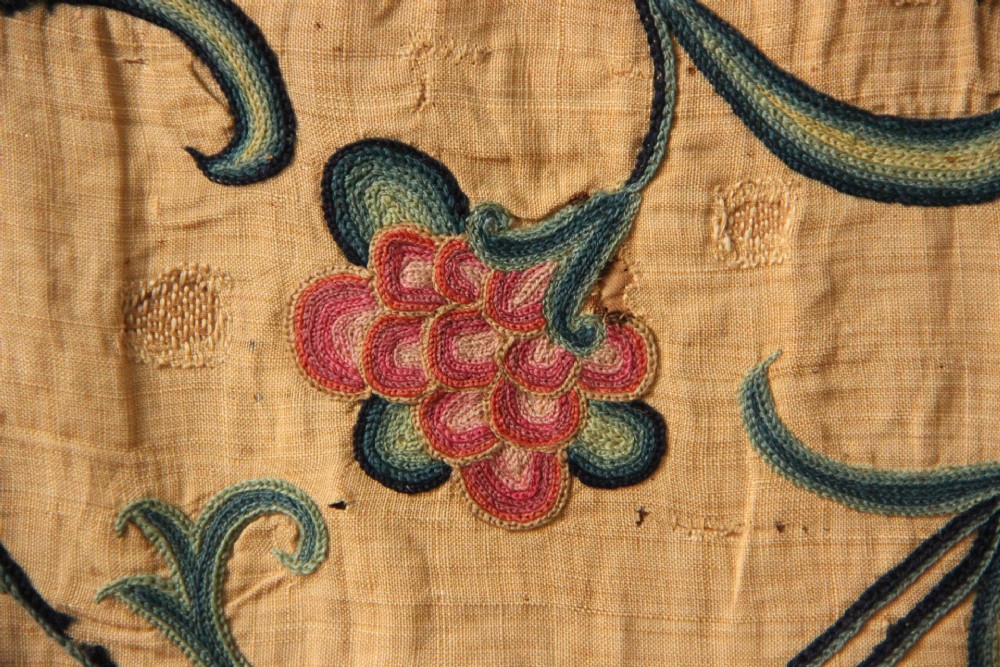 A large rectangular antique English crewelwork panel with intricate hand-embroidered floral tendrils in green, blue, and red wool on a cream background. View VIII