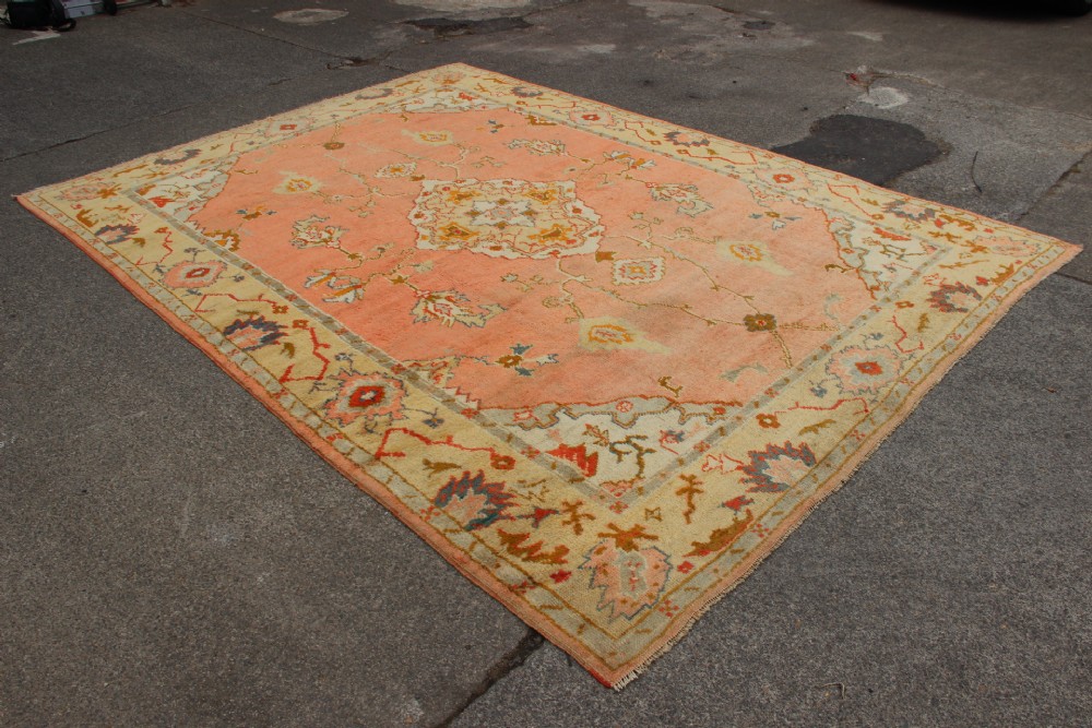 An antique hand-knotted wool carpet featuring a central medallion on a peach-coloured field surrounded by patterned floral borders. View II