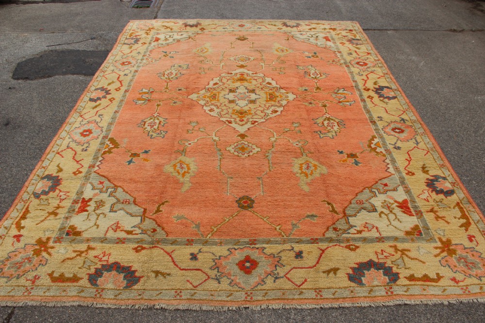 An antique hand-knotted wool carpet featuring a central medallion on a peach-coloured field surrounded by patterned floral borders. View V