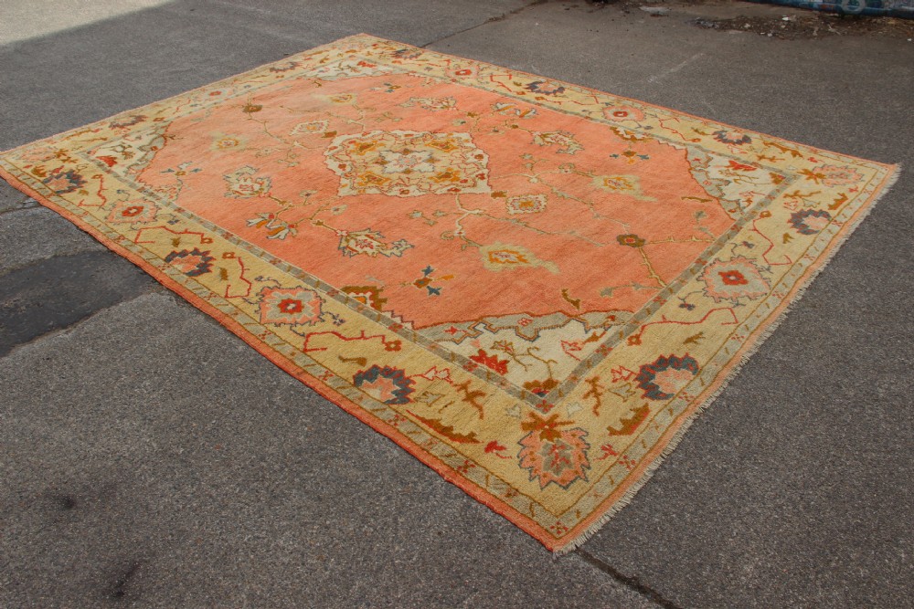 An antique hand-knotted wool carpet featuring a central medallion on a peach-coloured field surrounded by patterned floral borders. View VI
