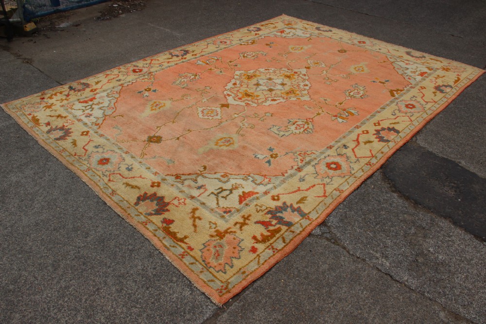 An antique hand-knotted wool carpet featuring a central medallion on a peach-coloured field surrounded by patterned floral borders. View VIII