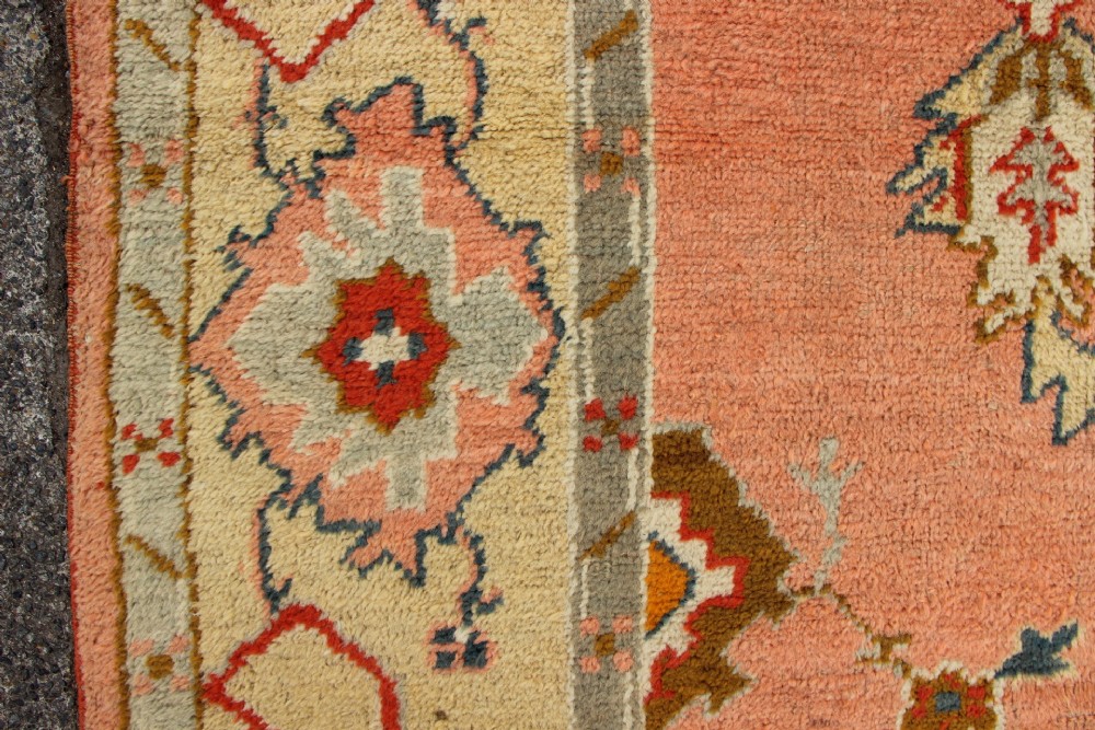 An antique hand-knotted wool carpet featuring a central medallion on a peach-coloured field surrounded by patterned floral borders. View IX