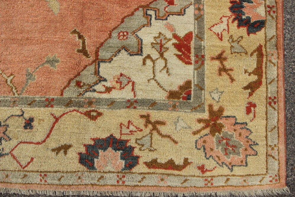 An antique hand-knotted wool carpet featuring a central medallion on a peach-coloured field surrounded by patterned floral borders. View XI