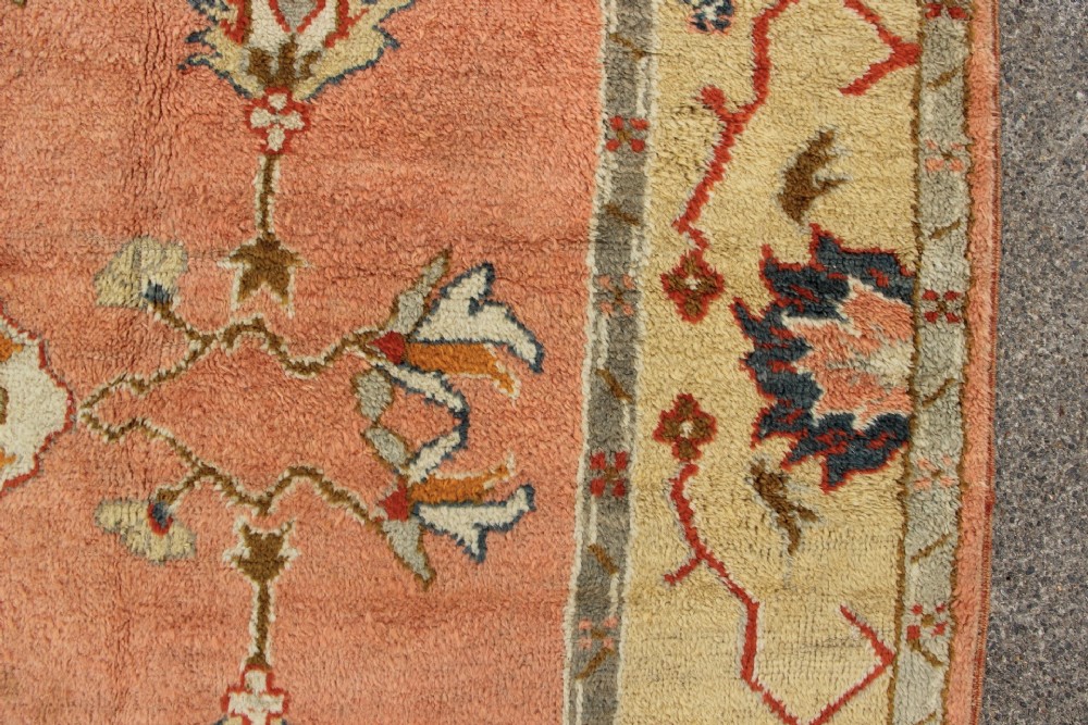 An antique hand-knotted wool carpet featuring a central medallion on a peach-coloured field surrounded by patterned floral borders. View XII