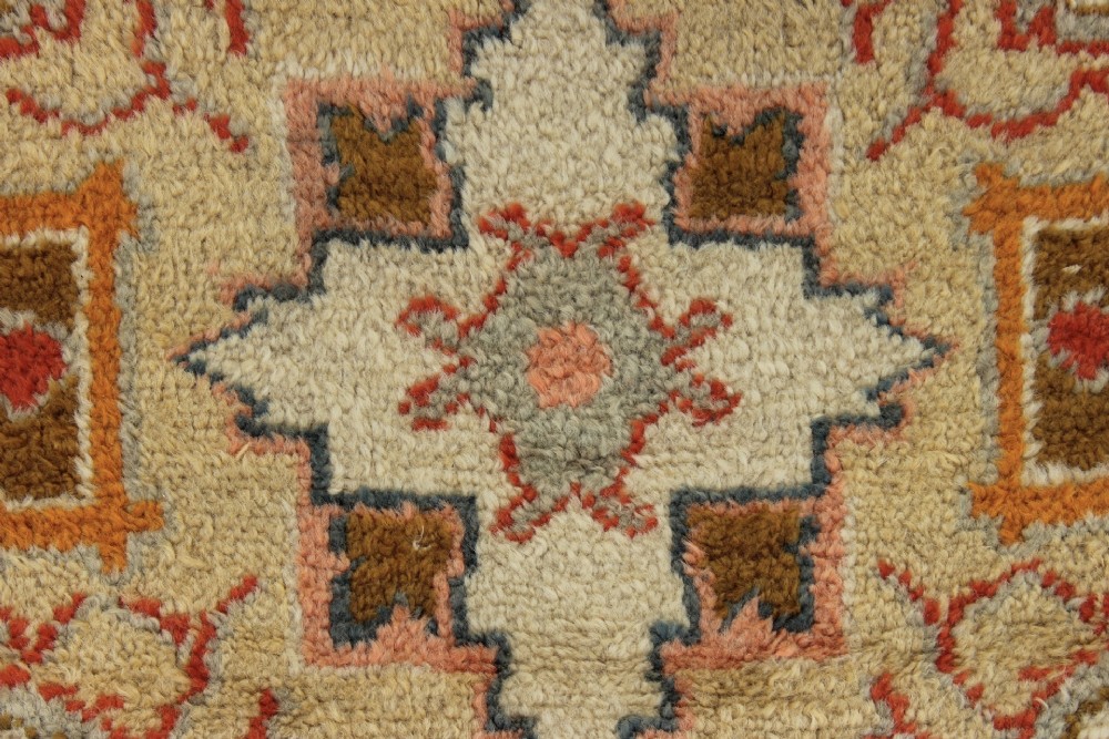 An antique hand-knotted wool carpet featuring a central medallion on a peach-coloured field surrounded by patterned floral borders. View XIV