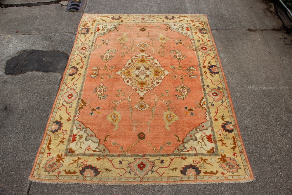 An antique hand-knotted wool carpet featuring a central medallion on a peach-coloured field surrounded by patterned floral borders. View XV