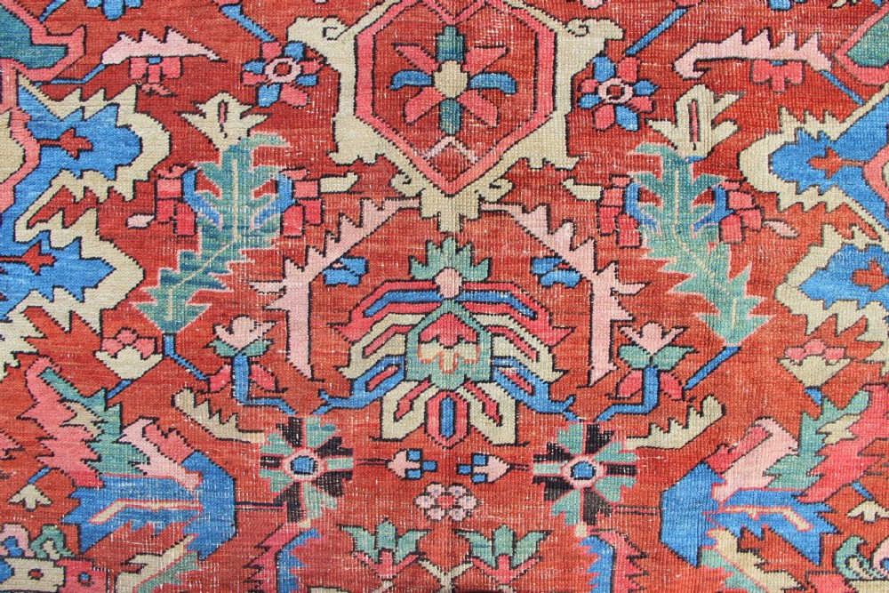 An antique hand-knotted Heriz carpet featuring a terracotta red field with central geometric motifs and a navy blue patterned border. View XIV