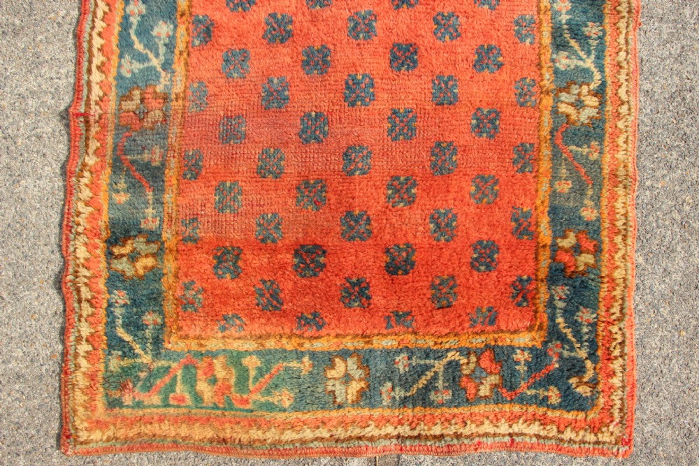 An extra long, narrow antique Turkish Oushak runner featuring a terracotta central field with small repeating geometric motifs enclosed within a dark blue-green patterned border. View IV