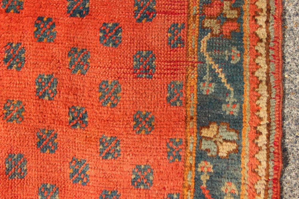 An extra long, narrow antique Turkish Oushak runner featuring a terracotta central field with small repeating geometric motifs enclosed within a dark blue-green patterned border. View VIII