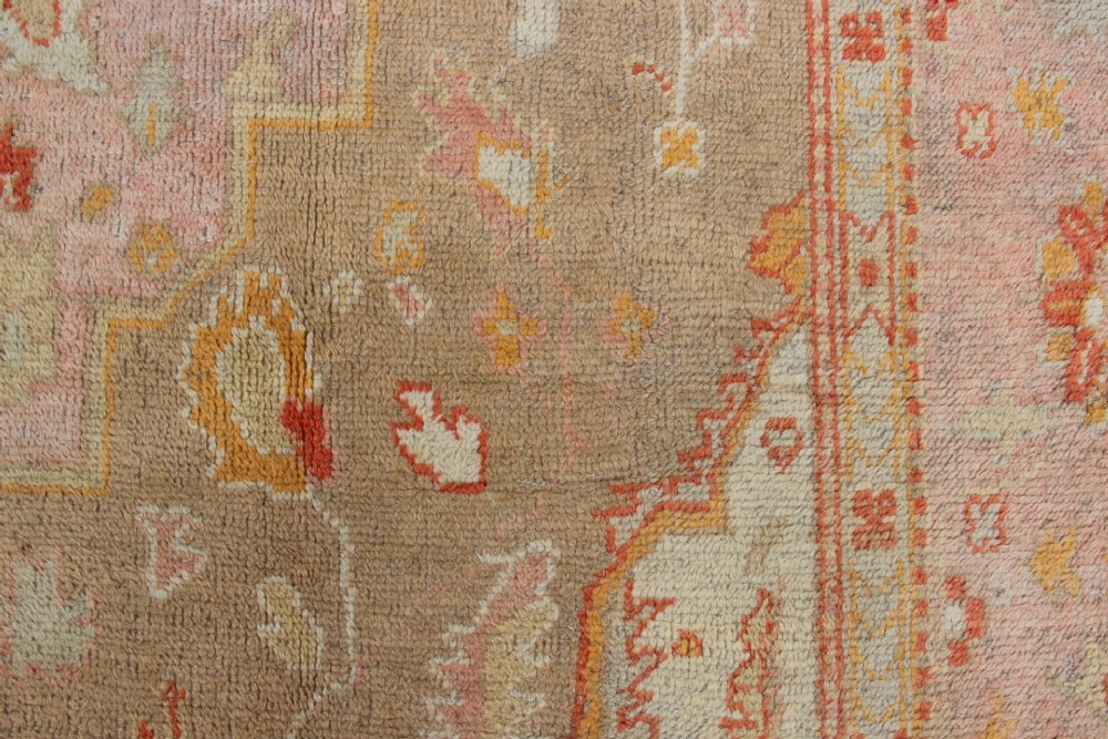 A large hand-knotted wool Oushak carpet displaying a central star medallion, angular floral spandrels, and a pastel palette of pale pink, cream, and beige. View VI