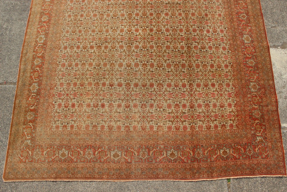 A large rectangular hand-knotted Persian Tabriz wool carpet featuring an all-over repeating geometric and floral pattern in terracotta, rust red, and beige framed by a complex multi-band border. View II