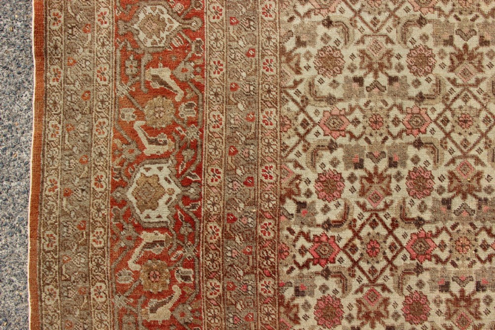 A large rectangular hand-knotted Persian Tabriz wool carpet featuring an all-over repeating geometric and floral pattern in terracotta, rust red, and beige framed by a complex multi-band border. View VI