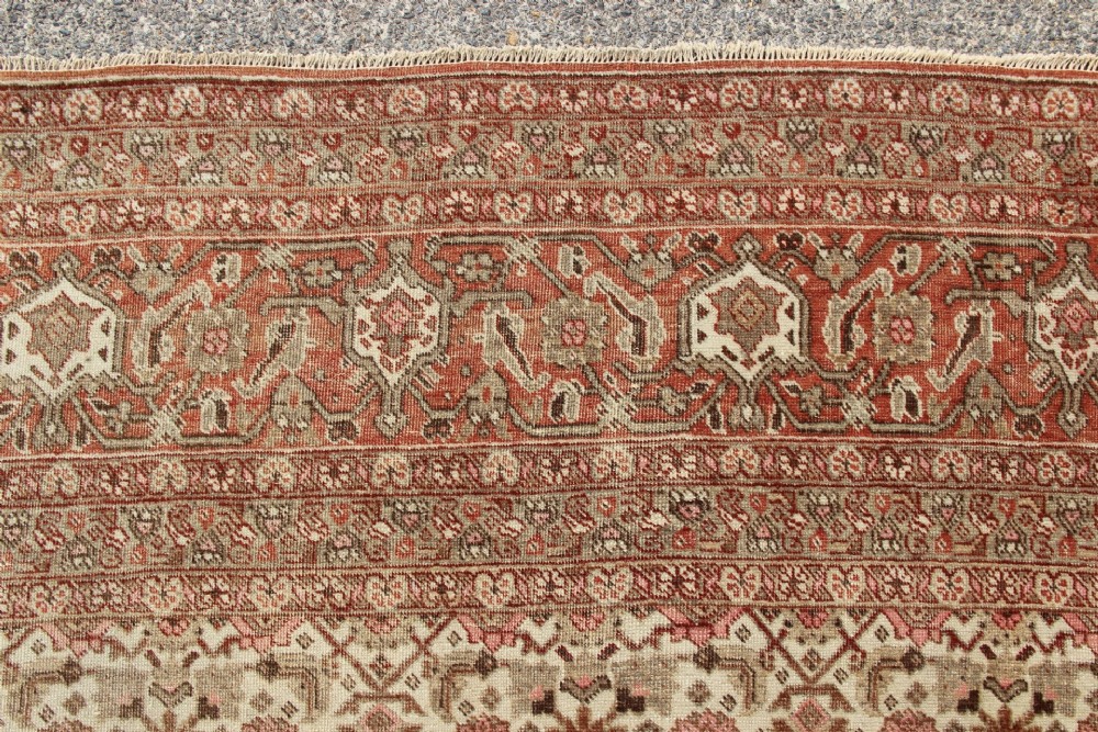 A large rectangular hand-knotted Persian Tabriz wool carpet featuring an all-over repeating geometric and floral pattern in terracotta, rust red, and beige framed by a complex multi-band border. View VII