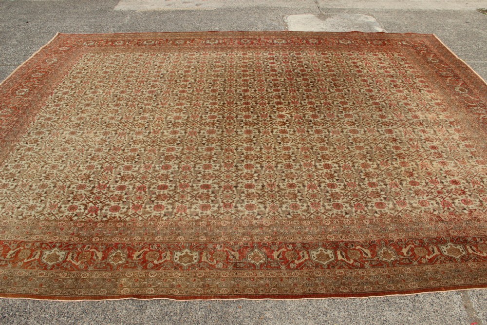 A large rectangular hand-knotted Persian Tabriz wool carpet featuring an all-over repeating geometric and floral pattern in terracotta, rust red, and beige framed by a complex multi-band border. View IX