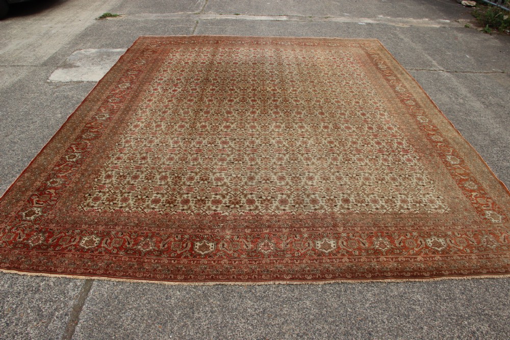 A large rectangular hand-knotted Persian Tabriz wool carpet featuring an all-over repeating geometric and floral pattern in terracotta, rust red, and beige framed by a complex multi-band border. View XI