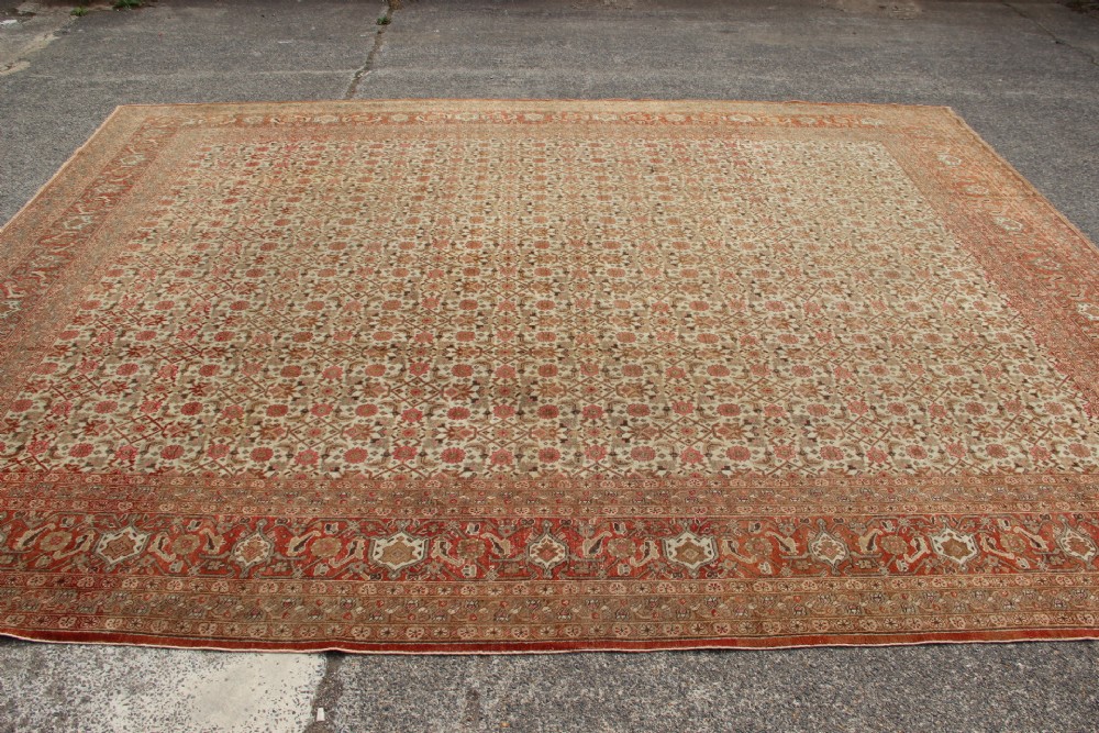 A large rectangular hand-knotted Persian Tabriz wool carpet featuring an all-over repeating geometric and floral pattern in terracotta, rust red, and beige framed by a complex multi-band border. View XIII