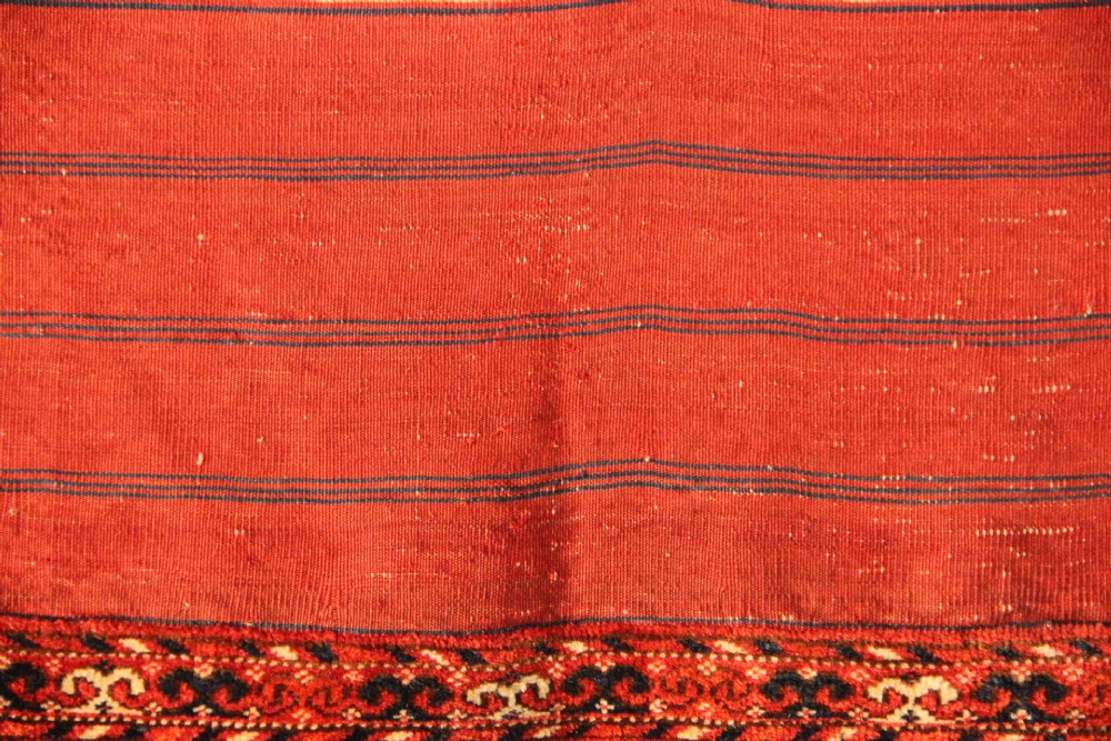 A large mid-19th century Tekke Turkoman hand-knotted wool main carpet featuring repeating geometric gol motifs on a deep red field with woven borders. View IX