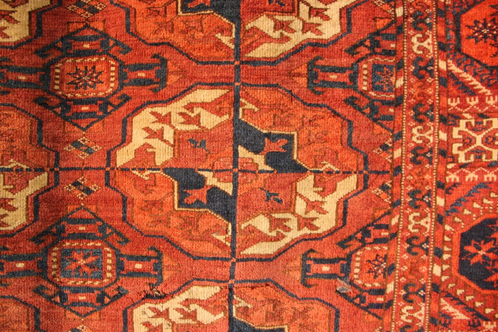 A large mid-19th century Tekke Turkoman hand-knotted wool main carpet featuring repeating geometric gol motifs on a deep red field with woven borders. View XII
