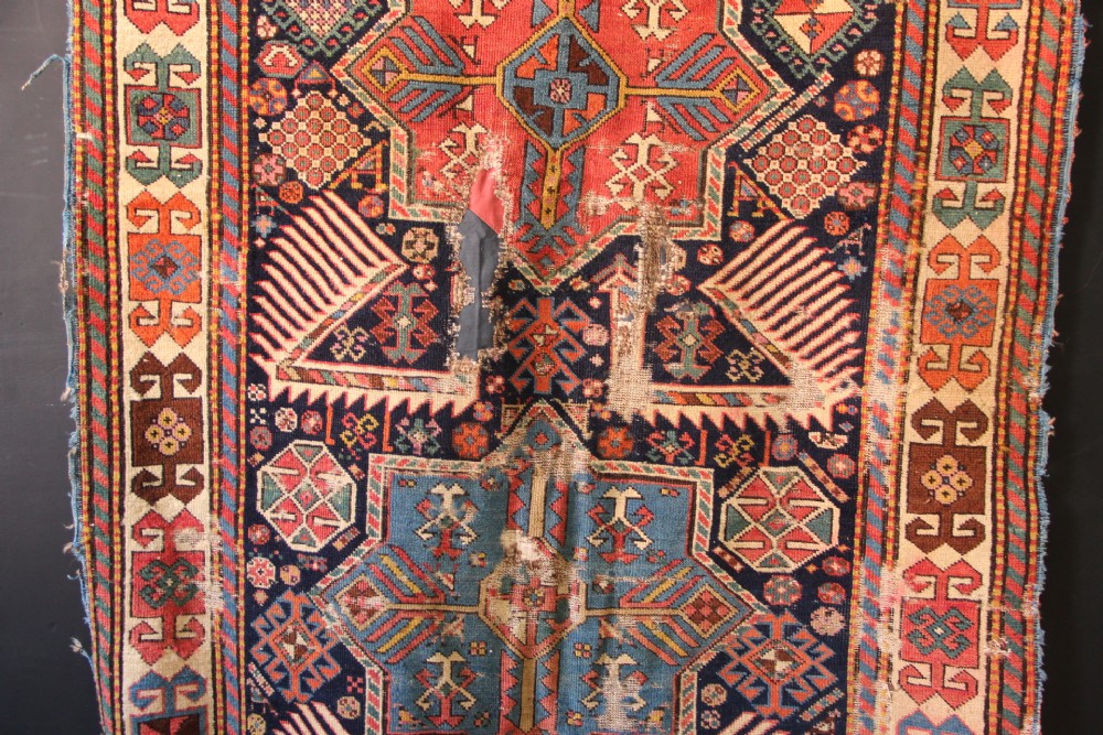 A long hand-knotted antique Caucasian Akstafa wool rug featuring geometric star medallions, stylized bird motifs, and a patterned border on a navy ground. View III