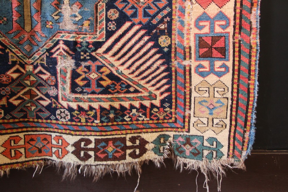 A long hand-knotted antique Caucasian Akstafa wool rug featuring geometric star medallions, stylized bird motifs, and a patterned border on a navy ground. View V