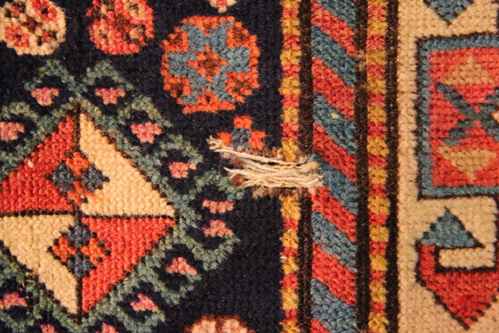 A long hand-knotted antique Caucasian Akstafa wool rug featuring geometric star medallions, stylized bird motifs, and a patterned border on a navy ground. View X