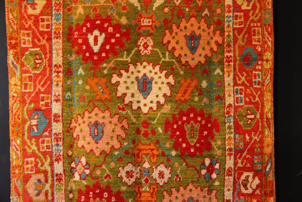 An antique hand-knotted Oushak wool rug featuring an olive green field with soft red, pink, and cream floral medallions surrounded by a terracotta patterned border. View II