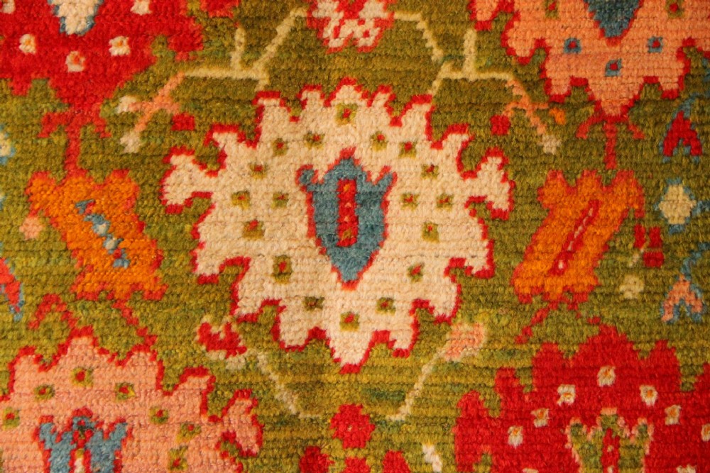 An antique hand-knotted Oushak wool rug featuring an olive green field with soft red, pink, and cream floral medallions surrounded by a terracotta patterned border. View III