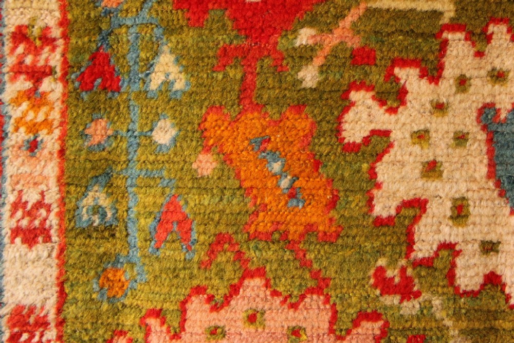An antique hand-knotted Oushak wool rug featuring an olive green field with soft red, pink, and cream floral medallions surrounded by a terracotta patterned border. View IX