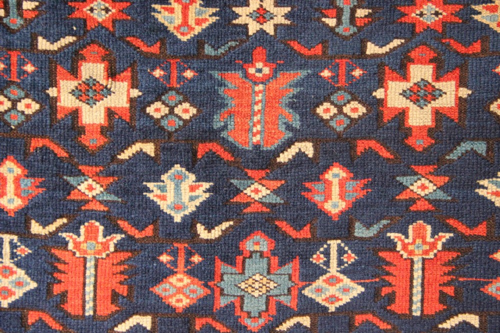 An antique Caucasian Kuba wool prayer rug featuring a dark navy field filled with small geometric motifs beneath a stepped arch border. View VII