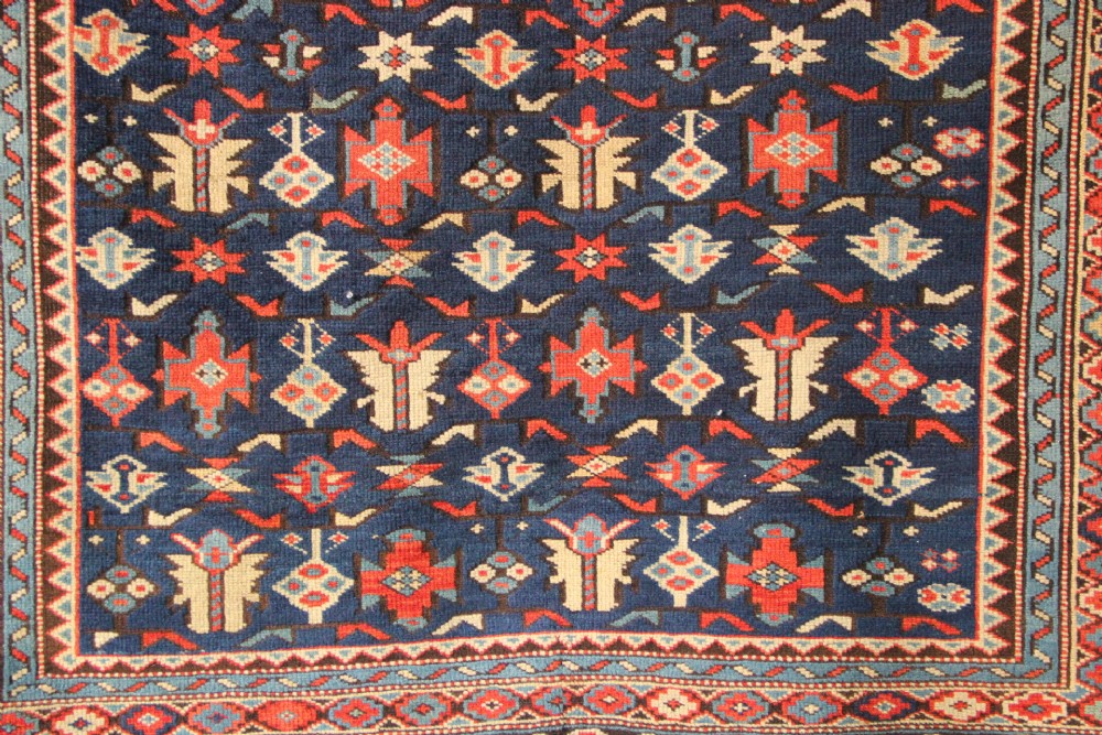 An antique Caucasian Kuba wool prayer rug featuring a dark navy field filled with small geometric motifs beneath a stepped arch border. View VIII