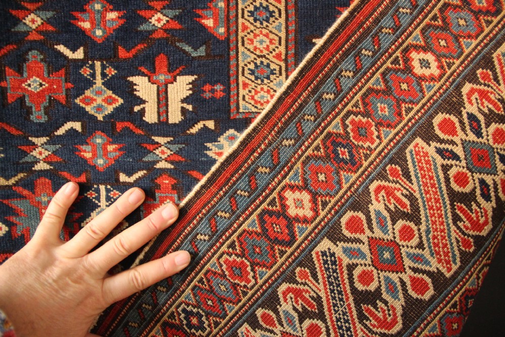 An antique Caucasian Kuba wool prayer rug featuring a dark navy field filled with small geometric motifs beneath a stepped arch border. View XI