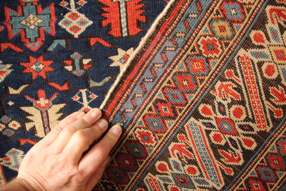 An antique Caucasian Kuba wool prayer rug featuring a dark navy field filled with small geometric motifs beneath a stepped arch border. View XII