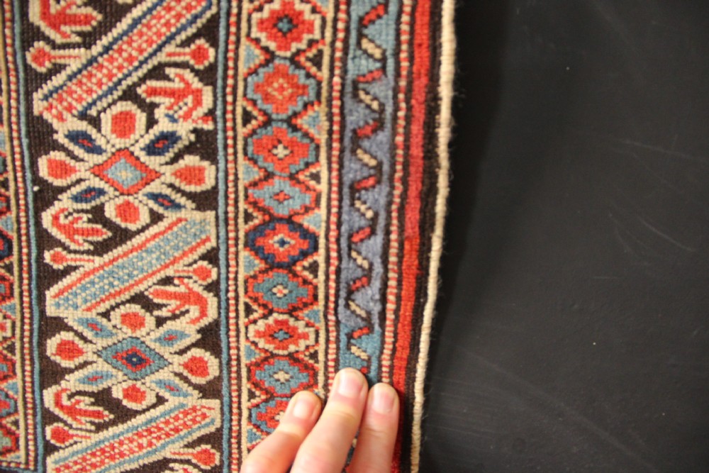An antique Caucasian Kuba wool prayer rug featuring a dark navy field filled with small geometric motifs beneath a stepped arch border. View XIII
