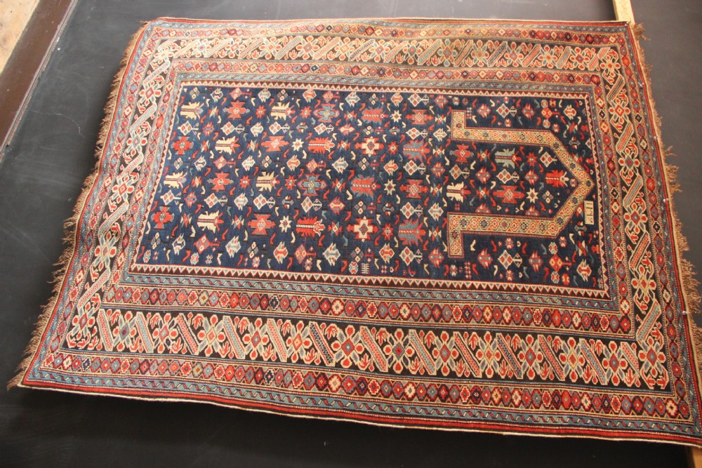 An antique Caucasian Kuba wool prayer rug featuring a dark navy field filled with small geometric motifs beneath a stepped arch border. View XIV