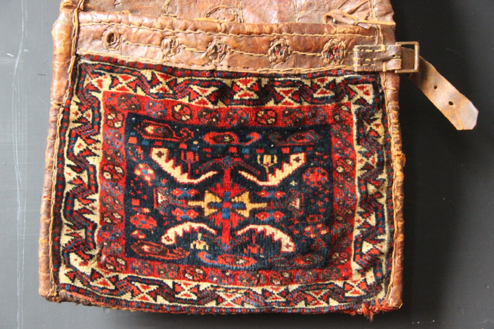 An antique miniature Khamseh tribal saddlebag featuring two hand-woven wool panels with deep red and navy geometric bird motifs joined by a leather centre section with straps. View III