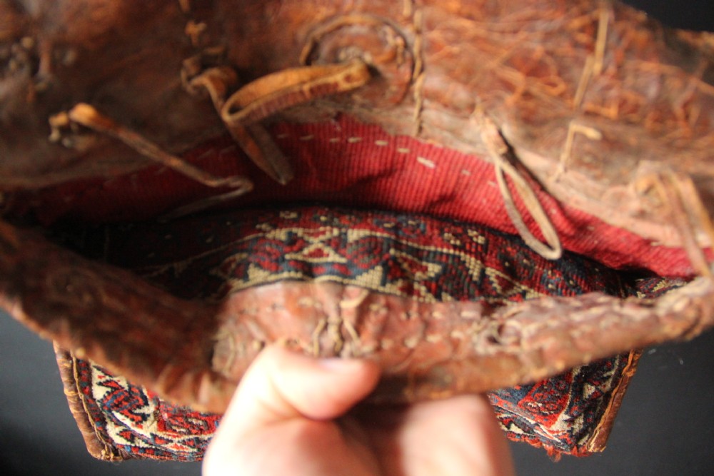 An antique miniature Khamseh tribal saddlebag featuring two hand-woven wool panels with deep red and navy geometric bird motifs joined by a leather centre section with straps. View V