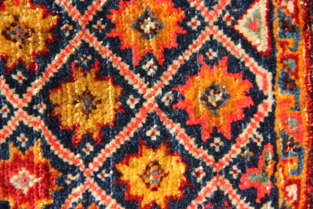 A handwoven antique Qashqai chanteh featuring red, navy blue, and cream wool with geometric diamond lattices and floral medallion patterns. View IV