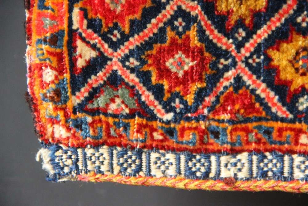 A handwoven antique Qashqai chanteh featuring red, navy blue, and cream wool with geometric diamond lattices and floral medallion patterns. View V