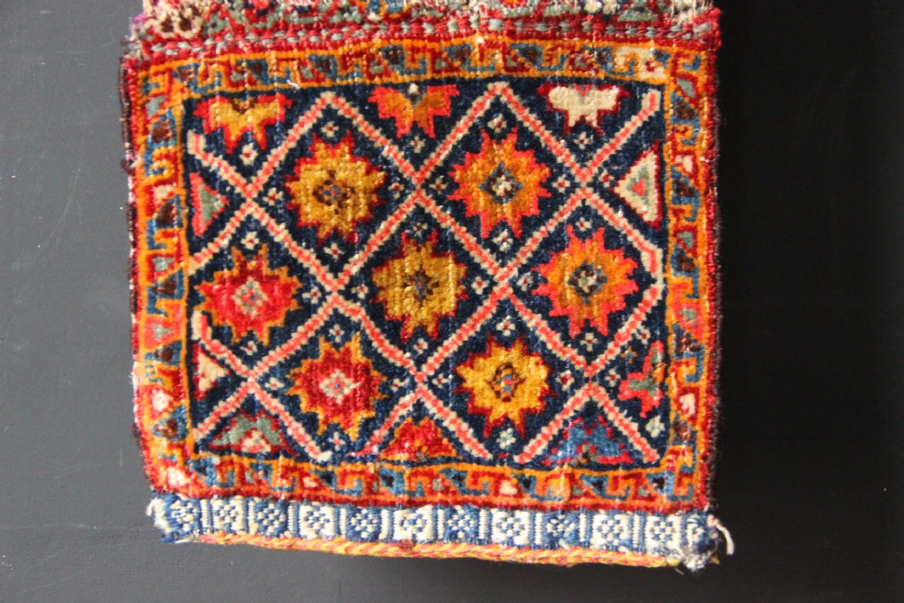 A handwoven antique Qashqai chanteh featuring red, navy blue, and cream wool with geometric diamond lattices and floral medallion patterns. View VI