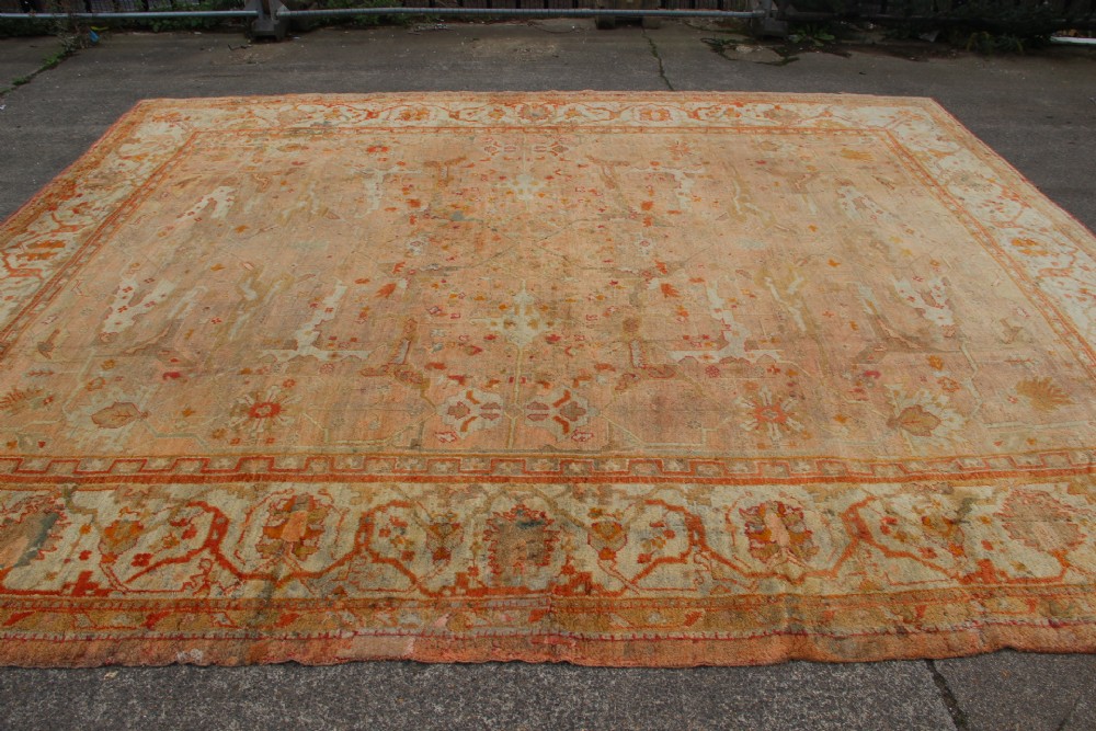 An oversized antique Turkish Oushak wool carpet featuring soft apricot, terracotta, and cream tones with traditional botanical borders and motifs. View II