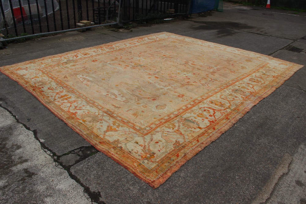 An oversized antique Turkish Oushak wool carpet featuring soft apricot, terracotta, and cream tones with traditional botanical borders and motifs. View III